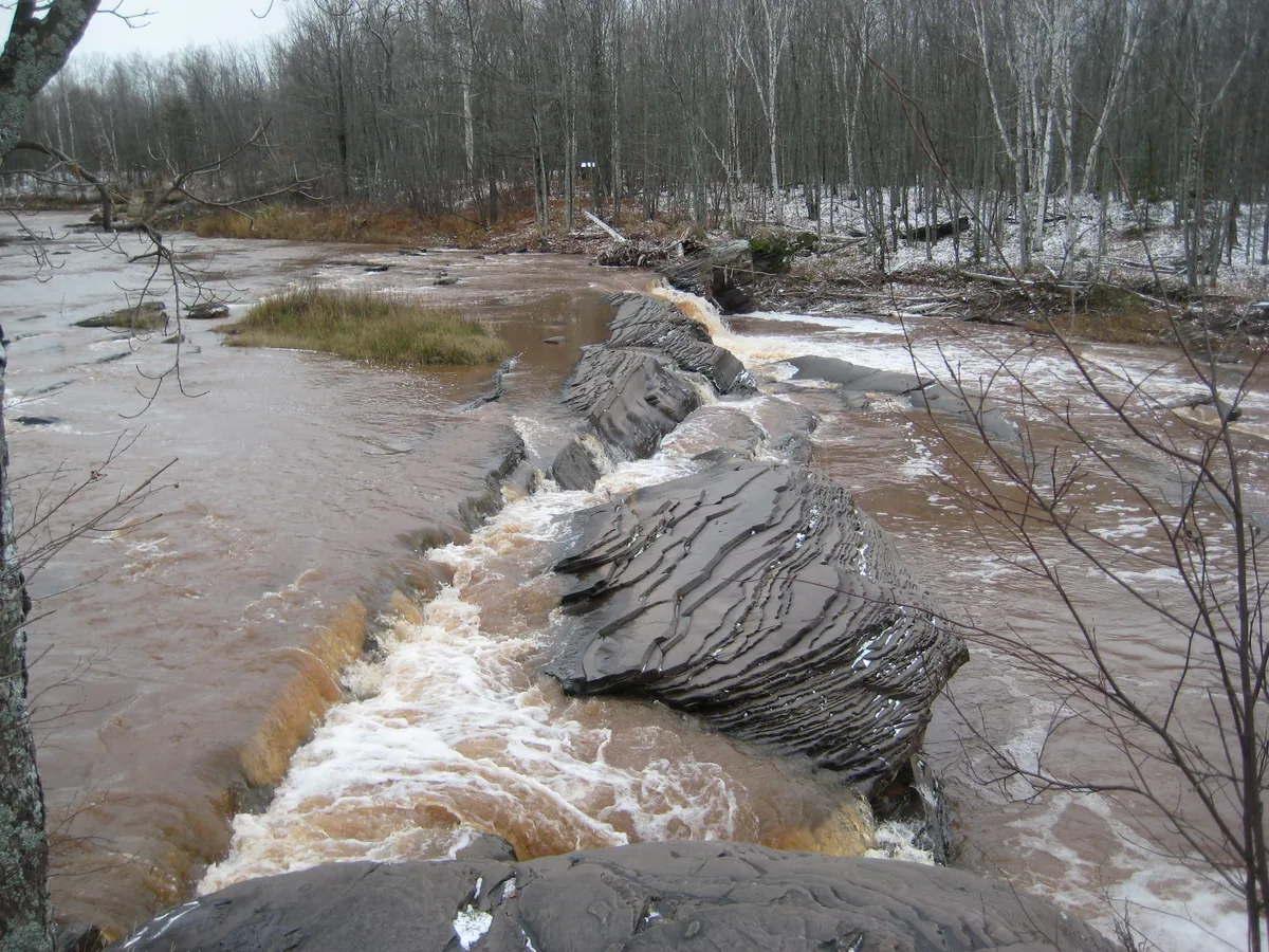 Brown waters over layered rocks