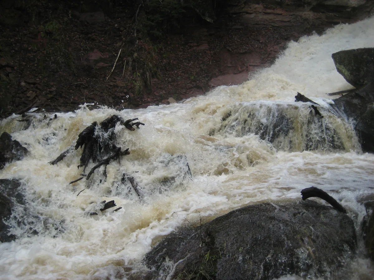 Swollen cascade drowning boulders and clutter