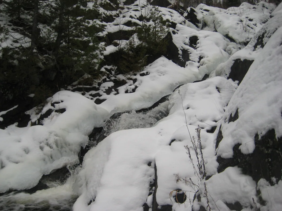 Boulders and water peaking through deep snow