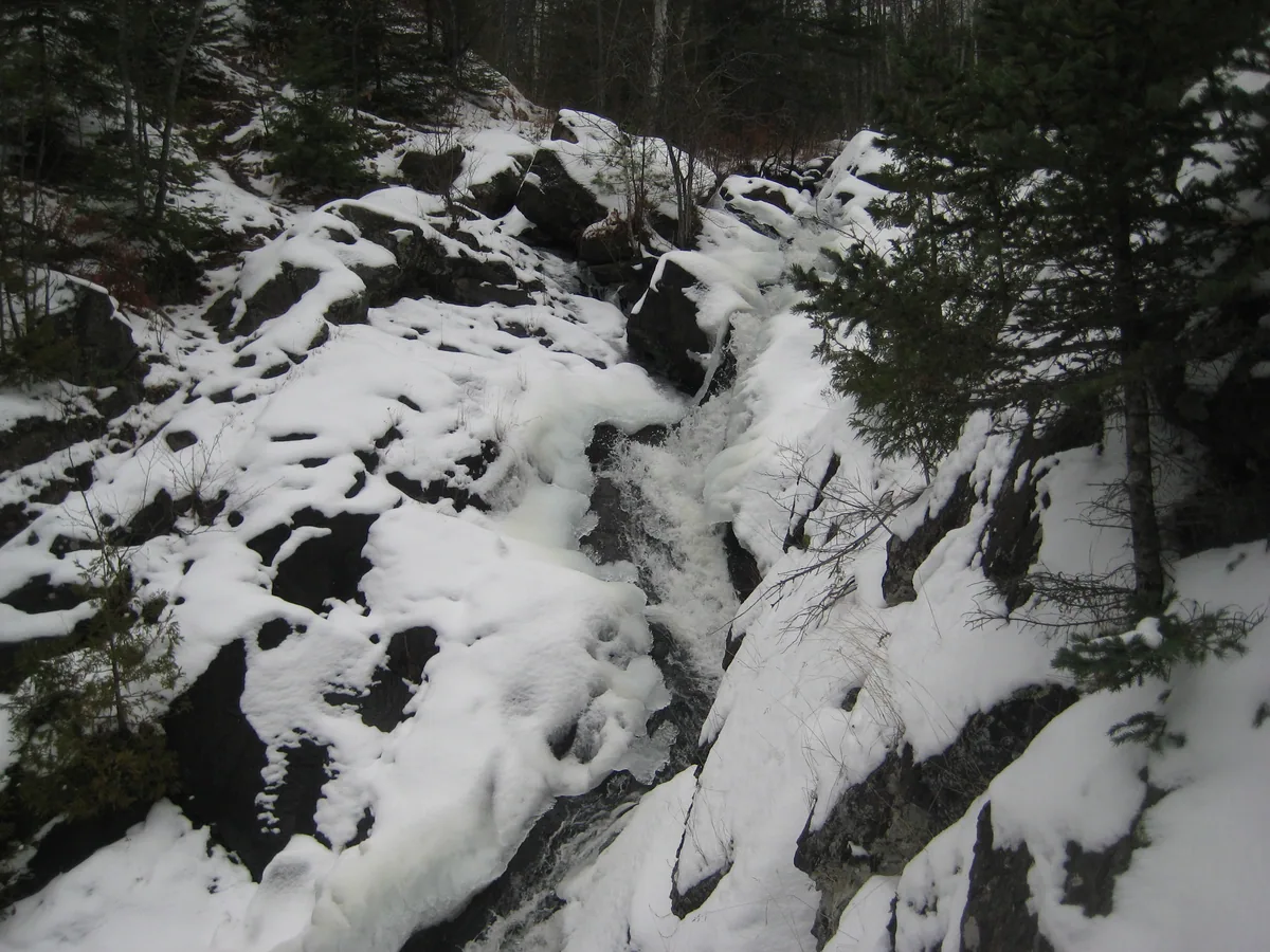 Cascading water surrounded by rock and snow