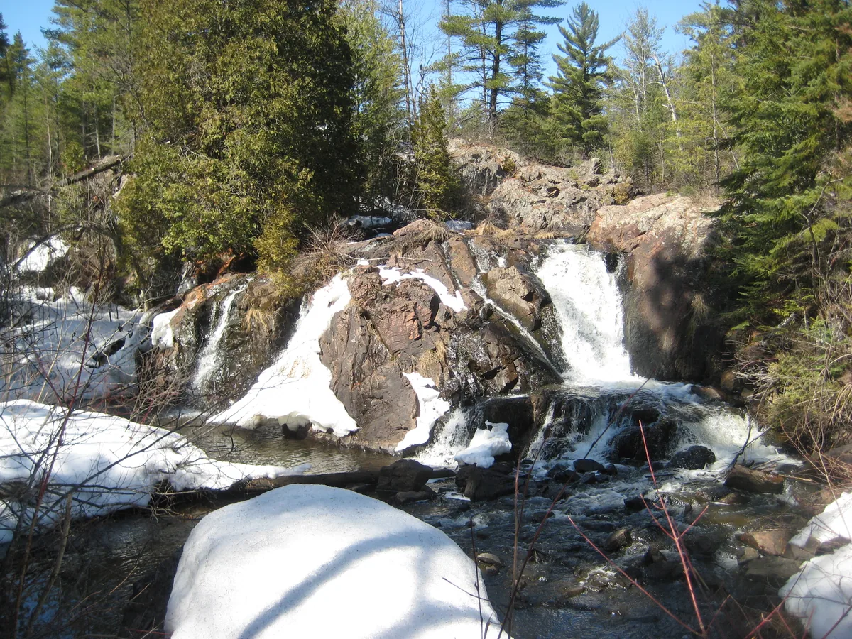 Snow and water plunging down into a swamp